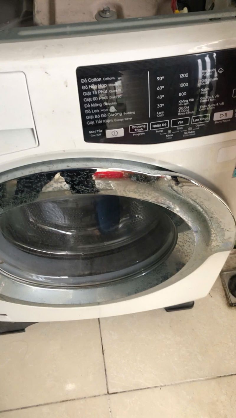 Mở nắp trên máy giặt cửa ngang để kiểm tra bên trong tại nhà khách ở Yên Phong